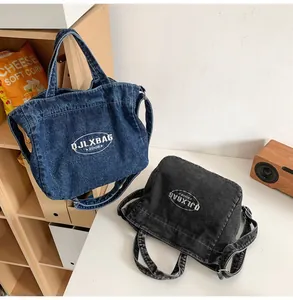 Detail of denim tote bags in blue and black with adjustable straps and logo print