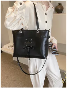 Detail of black tote bag with ballet-style bow lacing and metallic eyelets on leather