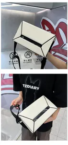 Detail of white geometric box bag with black trim and adjustable wide shoulder strap