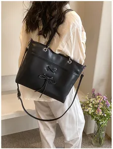 Detail of black ballet-style tote bag with decorative bow and premium PU leather texture