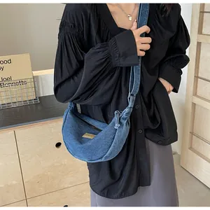 Vue latérale d'un sac bandoulière croissant en jean bleu porté par un mannequin