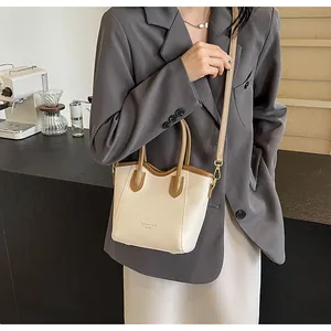Detail of color-block bucket bag with gold hooks and adjustable leather shoulder strap