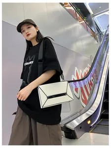 Outdoor shot of cream rectangular crossbody bag with geometric lines on escalator