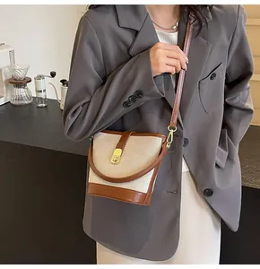 Detail of canvas bucket bag with brown leather trim and golden metal snap closure