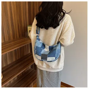 Detail of a patchwork denim hobo bag with adjustable silver buckle and stitching