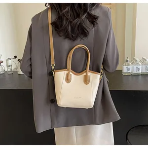 Detail of contrast color crossbody bag showing leather texture and fashion trend gold lettering