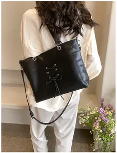 Detail view of black ballet-style tote bag with decorative bow and ribbon on model