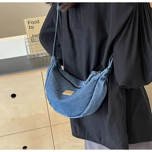 Détail du sac bandoulière en denim bleu en forme de lune avec logo et fermeture