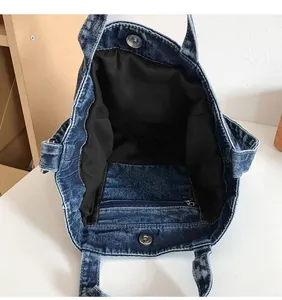 Interior view of denim tote bag showing black lining, inner zipper pocket and magnetic snap