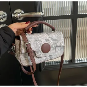 Detail of floral tapestry fabric handbag with brown leather straps and silver buckle