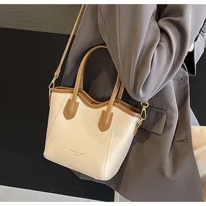 Detail of contrast color bucket bag in cream and brown with detachable shoulder strap