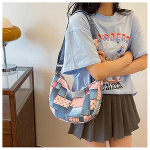 Detail of a patchwork crescent shoulder bag featuring blue denim and floral prints