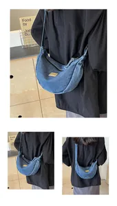 Détail du sac croissant en denim bleu avec fermeture éclair et écusson en cuir brun
