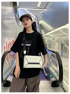 Detail of off-white crossbody bag with geometric black lines and wide strap on model