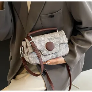 Close-up of vintage jacquard handbag with brown leather trim held by model
