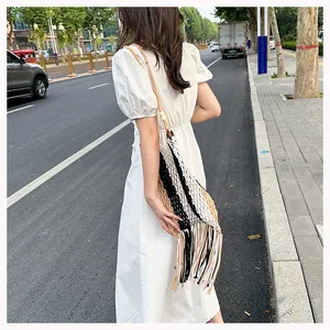 Detail of handmade woven beach bag featuring contrast color stitching and long tassels