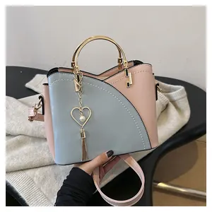 Dettaglio borsa a secchiello rosa e blu con manico dorato e ciondolo a cuore