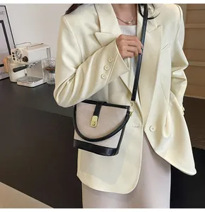 Detailed view of the beige canvas bucket bag with black leather trim and golden lock