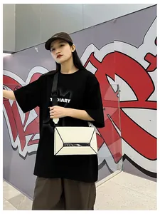 Detailed view of cream geometric crossbody bag with contrast straps in street style setting