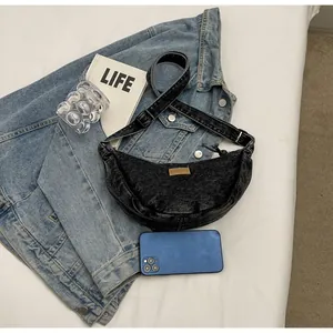 Détail du sac bandoulière croissant en jean noir avec sangle réglable et patch cuir
