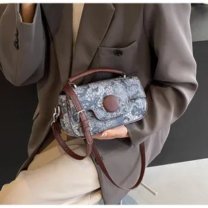Detail of vintage printed fabric handbag with brown leather straps and metal buckle