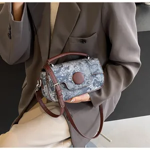 Detail of vintage blue floral fabric bag with brown leather strap and handle