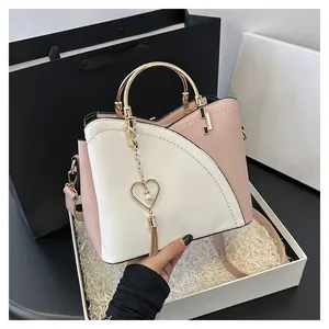 Dettaglio borsa a secchiello rosa e bianca con manico ad anello oro e nappa a cuore