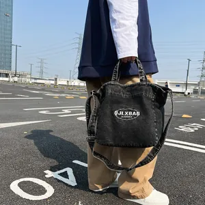 Large black denim canvas tote bag with adjustable shoulder strap and logo print