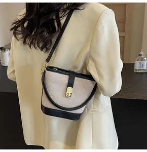 Detailed shot of beige canvas bucket bag with black leather trim and gold metal lock