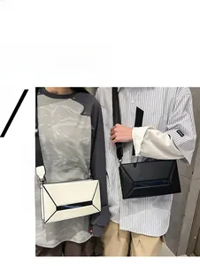 Detail of geometric shoulder bags in white and black with 3D structural paneling and wide strap