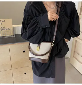Detail of contrast bucket bag with cream canvas, brown leather and gold metal buckle