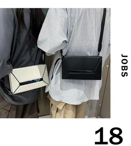 Detail view of large capacity geometric crossbody bags in black and cream leather finishes