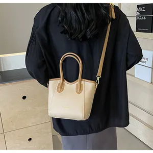 Detail of minimalist cream and brown tote bag showing gold rotating clasp and handle