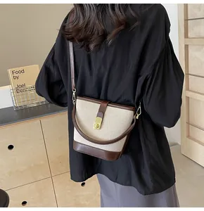 Detail of canvas bucket bag showing gold metal swivel lock and brown leather trim