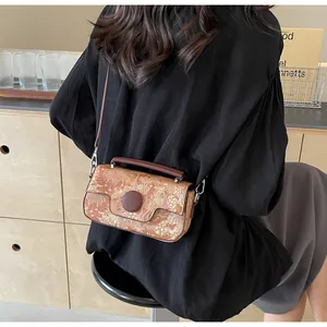 Detail of vintage patterned crossbody bag with brown leather strap in lifestyle setting