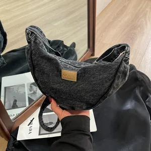 Sac bandoulière demi-lune en jean noir délavé avec logo vintage en cuir marron