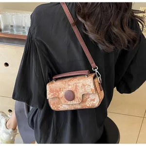 Close-up of retro floral print crossbody bag with brown leather strap and round buckle