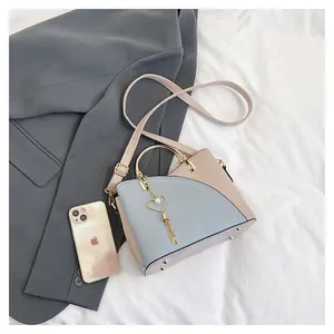 Dettaglio di cuciture a contrasto, hardware dorato e nappa cuore di perle sulla borsa