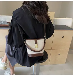 Detailed view of the canvas and leather bucket bag featuring elegant metal twist lock
