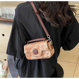 Detail of vintage brown printed crossbody bag showing textured flap and round buckle