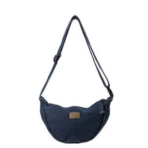 Sac bandoulière en denim bleu foncé en forme de croissant avec sangle réglable et patch