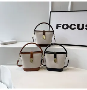 Detailed view of canvas bucket bags in brown, tan and black with leather accents