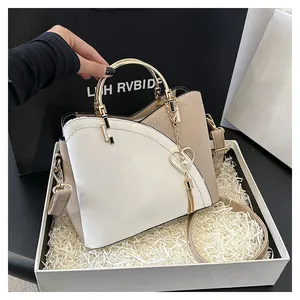 Dettaglio elegante borsa a secchiello bicolore con manico dorato e nappa a cuore in regalo