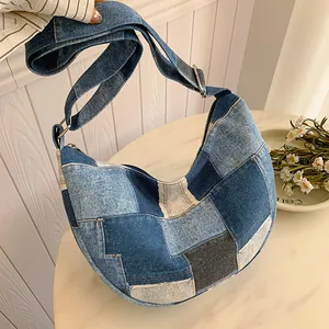 Fashionable denim patchwork crescent shoulder bag with adjustable strap on marble background