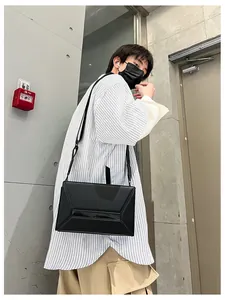 Male model wearing black geometric crossbody bag with trapezoid structure in urban street style