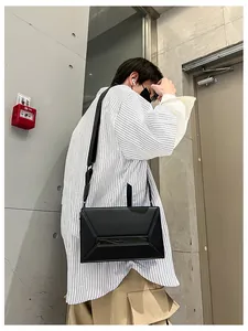 Minimalist black geometric crossbody bag with a wide strap and modern matte finish on a model