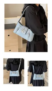 Detail of light blue croc-embossed underarm bag featuring silver floral metal buckle