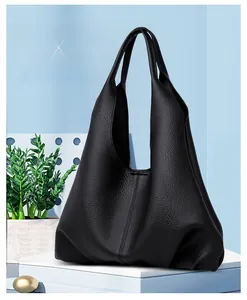Detail of black pebbled leather texture on a minimalist large hobo shoulder bag