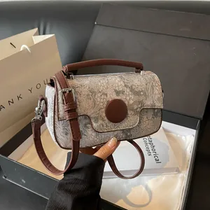 Vintage patterned handbag with brown leather handles and strap against gift boxes