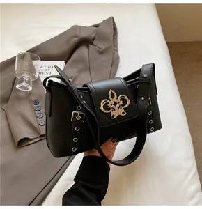 Close-up of black crocodile pattern faux leather bag with gold fleur-de-lis buckle